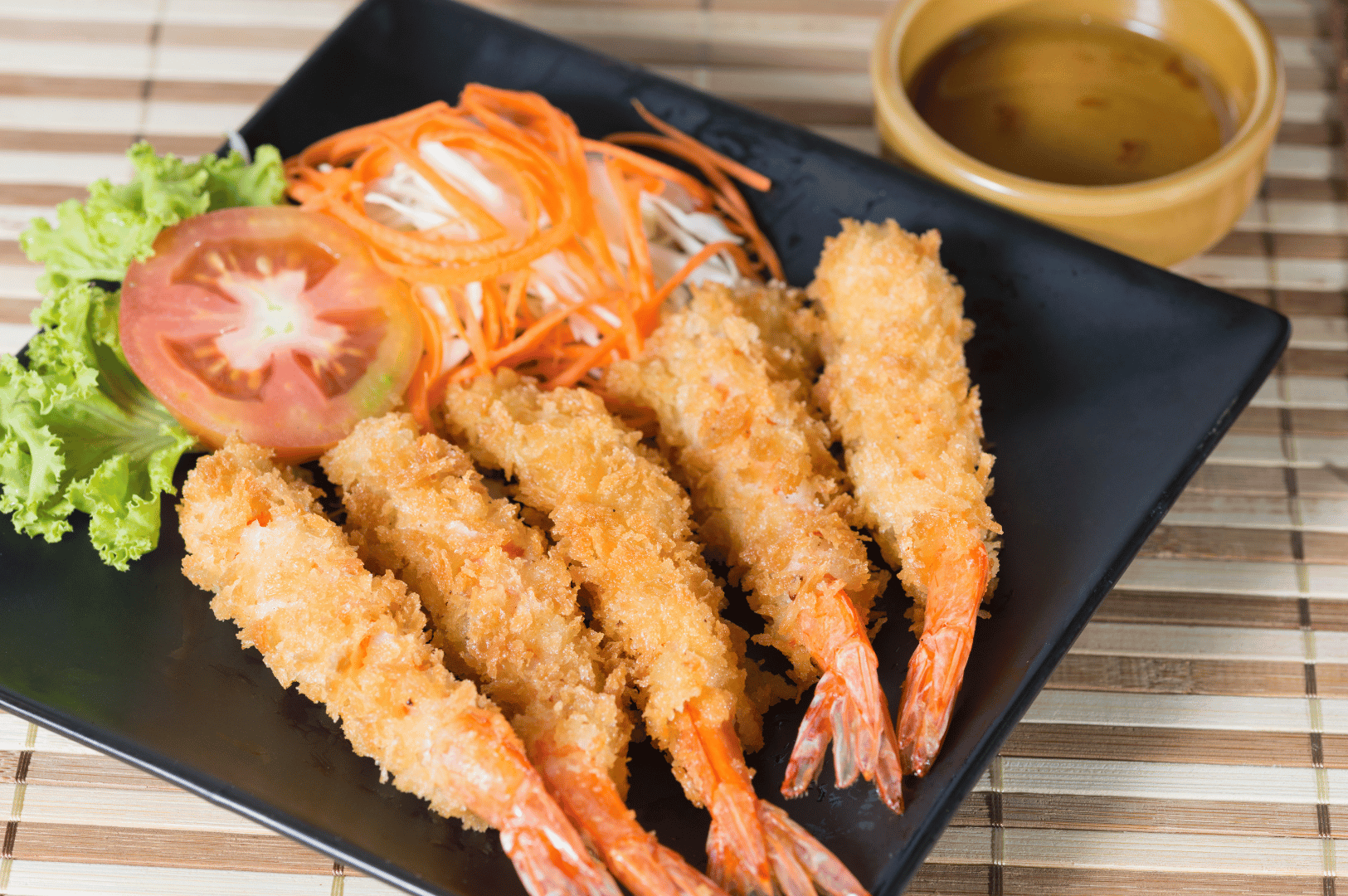 Crisp, golden tempura laid out on a sleek black plate, garnished with tomato, lettuce, and shredded radish—an elevated take on tempura technique at Yamato’s omakase in Singapore, where expert scrutiny meets visual precision and layered flavor.