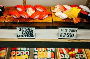 Fresh sashimi and sushi spread at a premium Japanese buffet, featuring thick slices of salmon sashimi, colorful sushi rolls, and traditional japanese dishes.